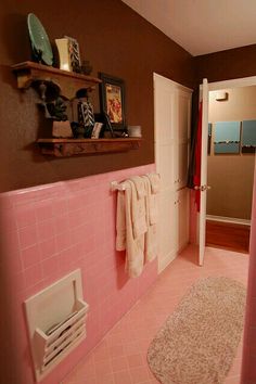 a bathroom with pink tile walls and flooring next to a doorway that leads to a hallway