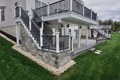 a house with stone and metal railings on the front porch, next to green grass