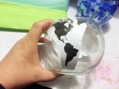 a person is holding a glass globe in their hand, with the world on it