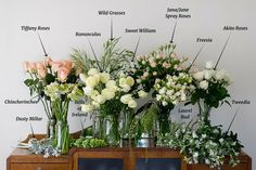 a bunch of vases that have flowers in them on top of a wooden table