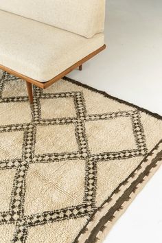 a white couch sitting on top of a rug next to a wooden table and chair