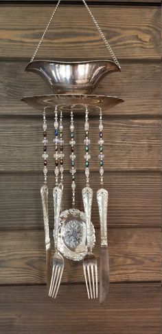 a silver plate hanging from the side of a wall with forks and spoons attached to it