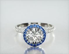 an engagement ring with blue and white stones on the side, set in yellow gold