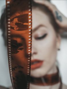 a woman with her eyes closed holding a film strip in front of her face