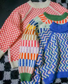 three sweaters sitting on top of a black and white checkered floor next to each other