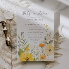 a baby shower with yellow flowers and greenery on the side, next to a bottle of cologne