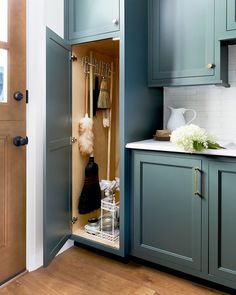 an open cabinet door in a kitchen with wooden flooring and blue painted cupboards