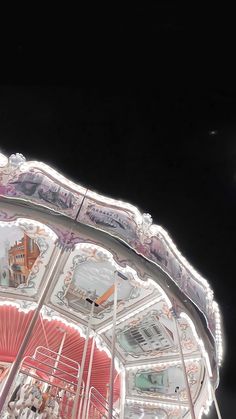 a merry go round at night with people on it's sides and the moon in the background