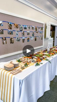 a long table with plates and bowls on it in front of a bulletin board filled with pictures