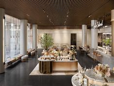 the interior of a modern restaurant with large windows and wooden ceilinging, along with tables and chairs