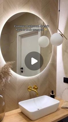 a bathroom sink sitting under a round mirror in front of a wall mounted faucet