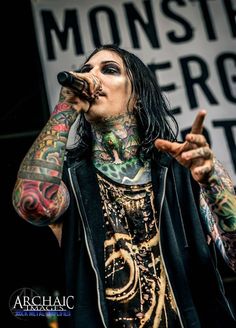 a man with long hair and tattoos holding a microphone