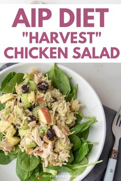 a white plate topped with chicken salad next to a fork and knife on top of a table