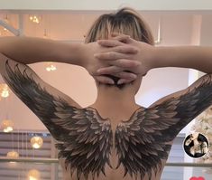 the back of a woman's body with large wings on her upper and shoulder