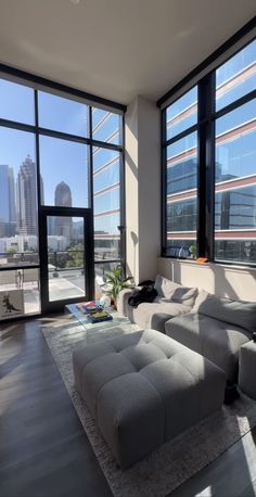 a living room filled with furniture and large windows overlooking the cityscape in the distance