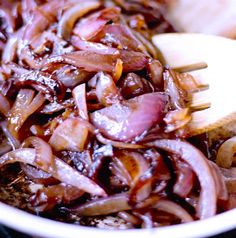 an onion dish is shown in a bowl with a wooden spoon and text overlay reads caramelized onions in red wine