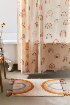 a bathroom with a bathtub, rug and shower curtain that has rainbows on it