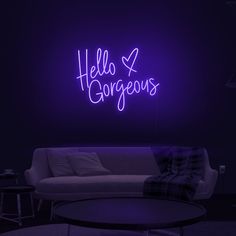 a living room with a white couch and purple neon sign on the wall above it