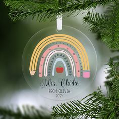 a glass ornament hanging from a christmas tree with a rainbow design on it