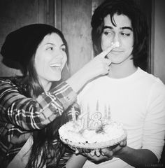 two people standing next to each other with a cake in front of them