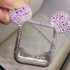 someone is holding up a minnie mouse head shaped mirror with some crystals on the front