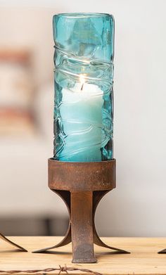 a blue candle sitting on top of a wooden table next to a glass container filled with water