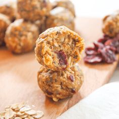 three oatmeal cookies stacked on top of each other with dried cranberries in the background