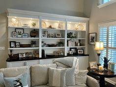 a living room filled with furniture and lots of shelves on the wall next to a window