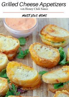 grilled cheese appetizers with honey chili sauce on a cutting board next to some bread