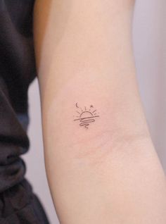 a woman's arm with a small sun tattoo on the left side of her arm