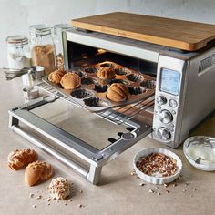 a toaster oven filled with muffins next to other baking supplies and ingredients