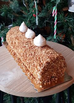 a piece of cake sitting on top of a wooden table next to a christmas tree