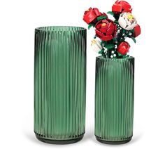 two green vases with red flowers in them