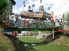 an upside down wooden bridge in the middle of a park with lots of chairs on it