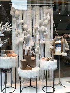 a window display with white fur and shoes on stools in front of the windows