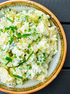 a bowl filled with potato salad on top of a wooden table