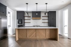 a large kitchen with wooden floors and gray cabinets, along with an island in the middle