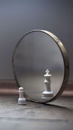 a mirror with a chess piece in front of it and a white pawn standing next to it