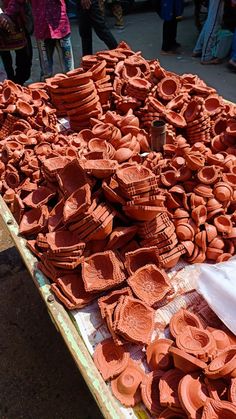 there are many clay pieces on the table for sale at this outdoor flea market, and they are ready to be sold