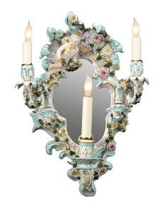 an ornate wall mirror with two candles in front of it and a cherub on the back