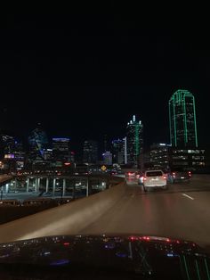 the city skyline is lit up at night with green and white lights in the foreground