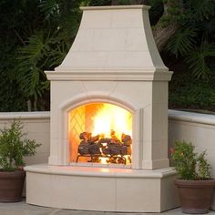 an outdoor fireplace with potted plants around it