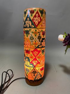 an orange vase sitting on top of a table next to a white flower pot and power cord