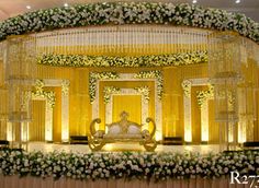 the stage is decorated with white flowers and greenery for an elegant wedding ceremony or reception