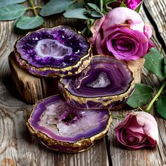 three amethysts sitting next to roses on a wooden table