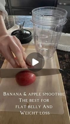 a person cutting up an apple on top of a wooden table next to a blender