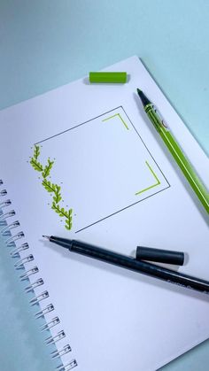 a notepad with green leaves on it next to two pens and a marker pen