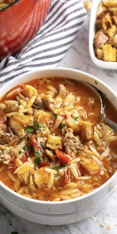 a white bowl filled with pasta and meat soup on top of a marble countertop