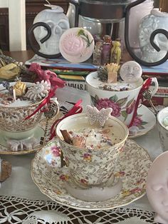 tea cups and saucers are sitting on a table with other items in the background