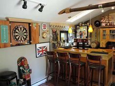 a room filled with lots of wooden furniture and darts on the wall next to a bar